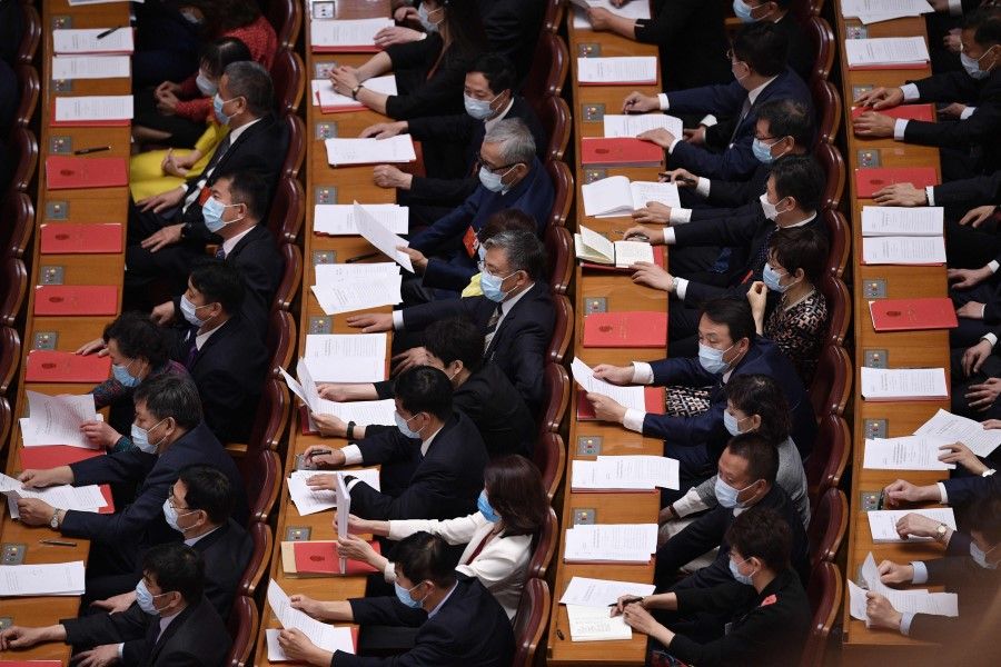 Delegates read through papers during the closing session of the National People's Congress at the Great Hall of the People in Beijing on 28 May 2020. (Nicolas Asfouri/AFP)