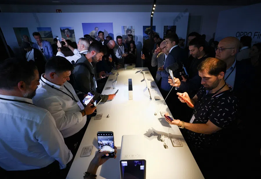 Attendees look at new models during a global launch event held by Chinese smartphone maker OPPO, in Barcelona, Spain, 28 October 2025. (Albert Gea/Reuters)