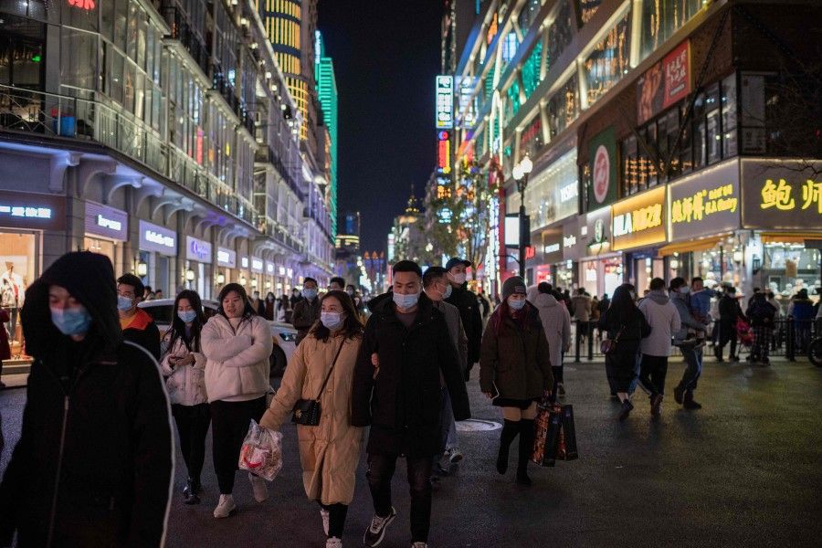 People wearing face masks walk on Jianghan street in Wuhan, China, on 10 January 2021. (Nicolas Asfouri/AFP)