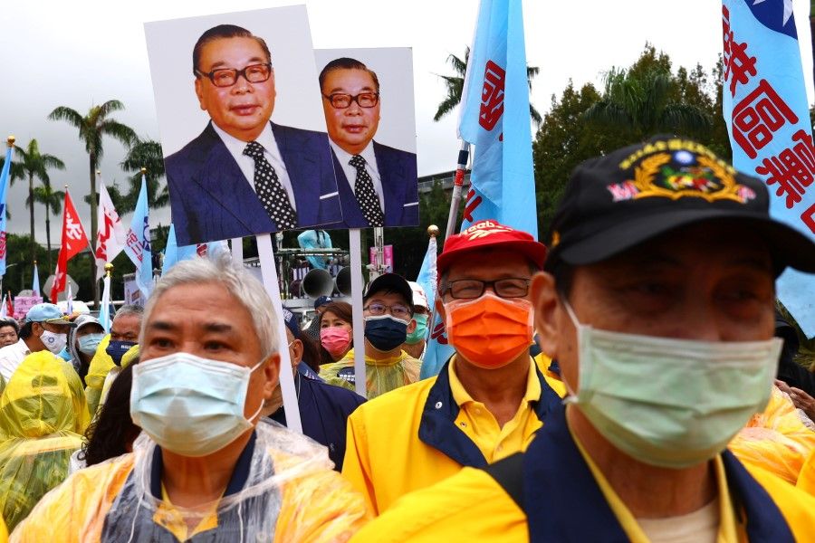 People holding signs showing former Taiwan President Chiang Ching-kuo as they take part in the annual Autumn Struggle labour protest, focusing on the opposition to the government's decision to allow imports of US pork containing ractopamine, an additive that enhances leanness, and other issues related to the referendum in Taipei, Taiwan, 12 December 2021. (Ann Wang/Reuters)