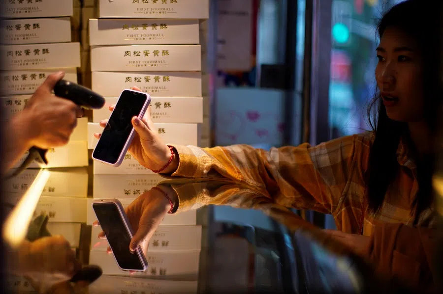A woman gets her phone's QR code of a digital payment service scanned at a food shop, in Shanghai, China, 10 October 2020. (Aly Song/Reuters)