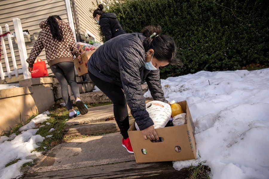 A family with Covid-19 carries free groceries inside which had been delivered by the non-profit Family Centers on 22 December 2020 in Stamford, Connecticut, US. (John Moore/Getty Images/AFP)