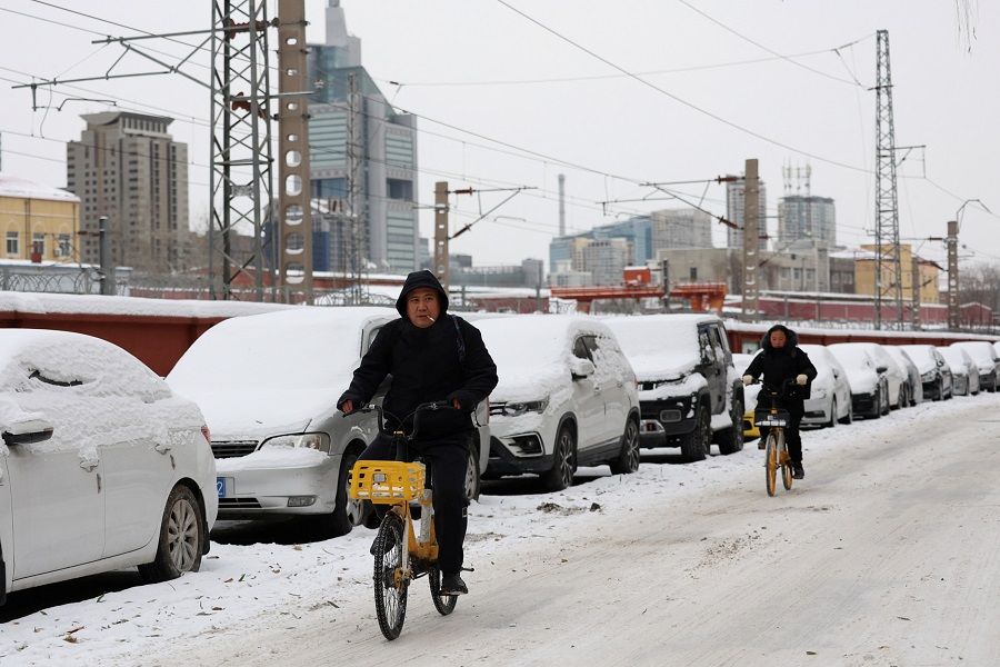 People ride bicycles on a road following snowfall in Beijing, China, on 15 December 2023. (Tingshu Wang/Reuters)