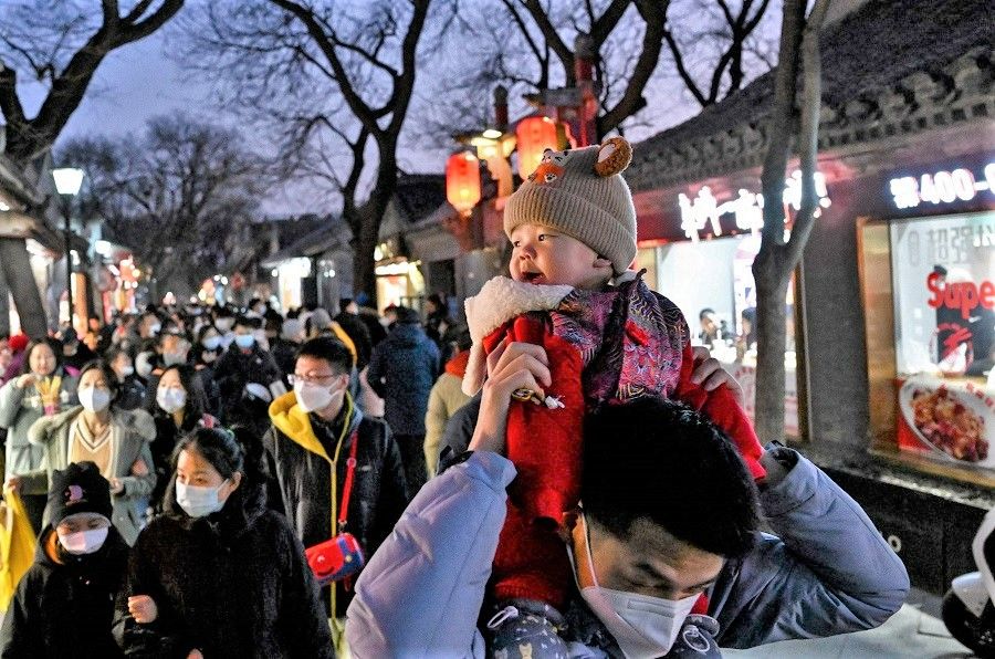 A child is carried along Nanluoguxiang alley in Beijing, China, on 22 January 2023. (Noel Celis/AFP)