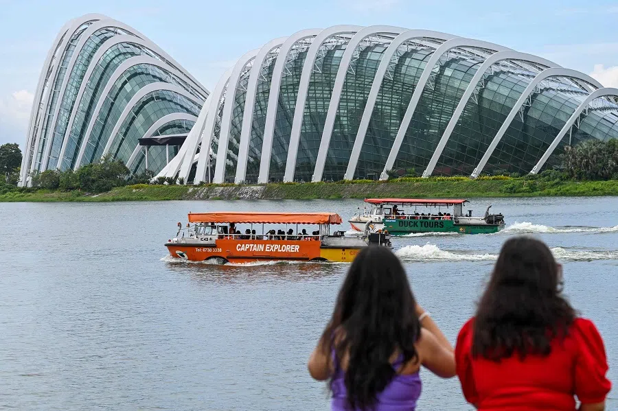 Boats pass by the flower domes of the Gardens by the Bay along Marina Bay in Singapore on 23 May 2024. (Roslan Rahman/AFP)