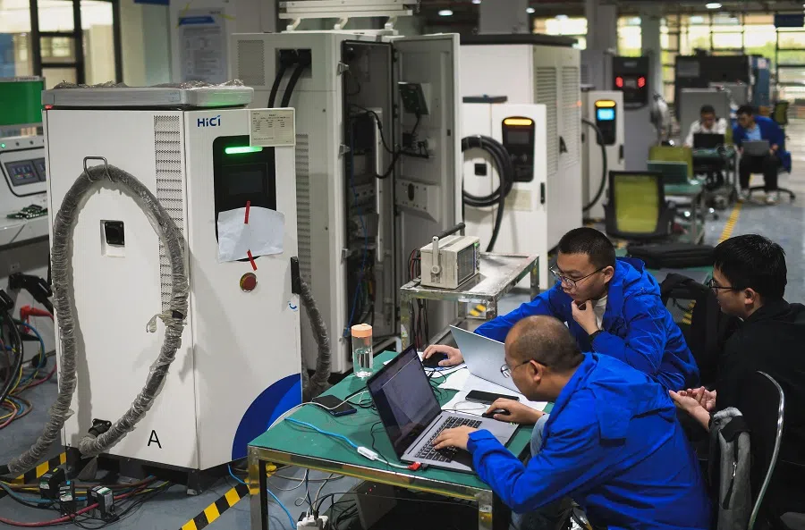 This photo taken on 17 April 2024 shows employees working at a factory that produces electric cars charging station for export in Wuhan, Hubei province, China.  (AFP)