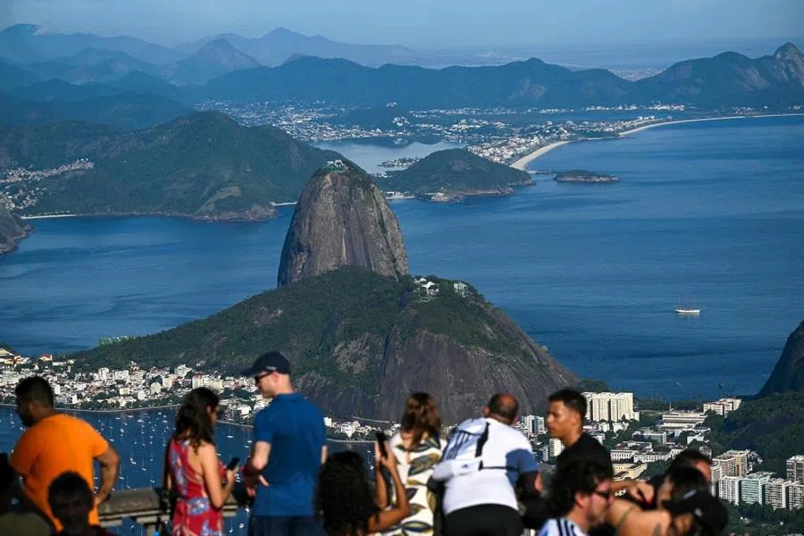 People look at Sugarloaf Mountain from the Christ the Redeemer balcony on Corcovado Mountain in Tijuca Forest National Park, in Rio de Janeiro, Brazil, on 10 December 2025.