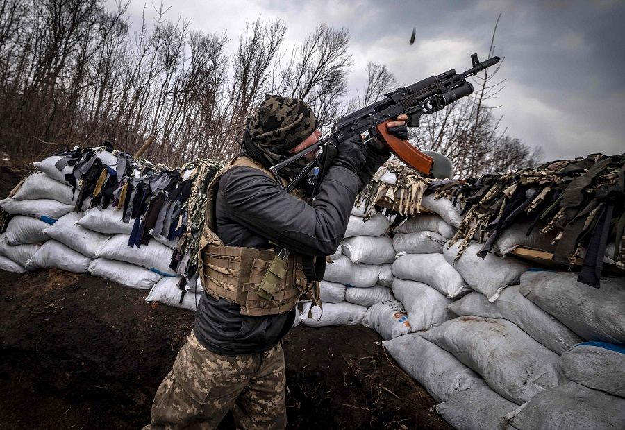 A Ukrainian serviceman shoots at a Russian drone with an assault rifle from a trench at the front line east of Kharkiv, Ukraine, on 31 March 2022. (Fadel Senna/AFP)