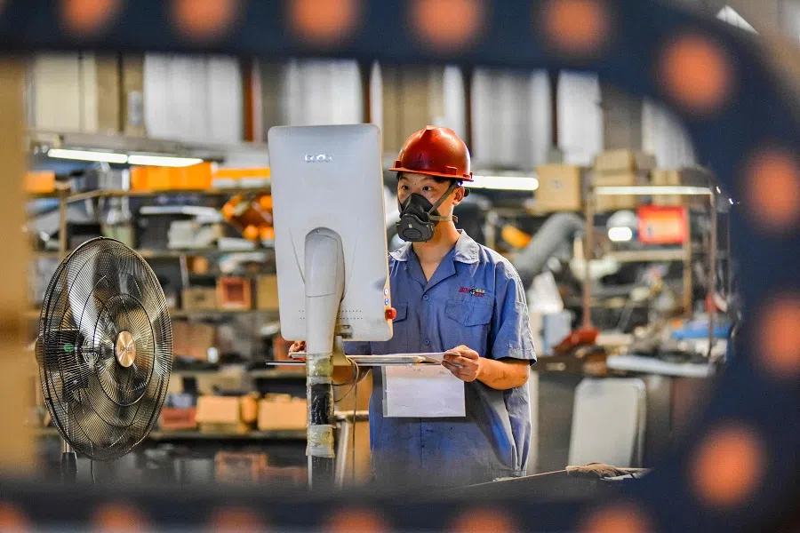An employee works on a machine part production line at a printing and packaging factory in Qingzhou, Shandong province, China, on 9 August 2024. (Stringer/AFP)