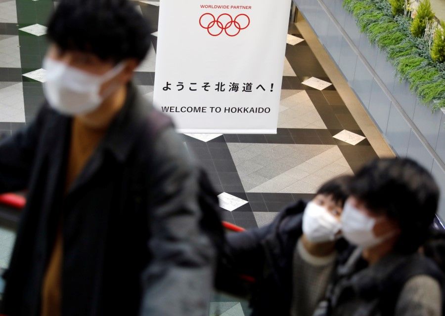 Passengers near a campaign banner for Tokyo 2020 Olympic Games at New Chitose Airport in Chitose, Hokkaido. (Issei Kato/REUTERS)