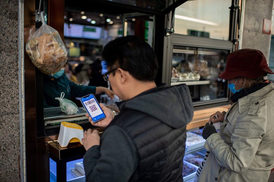 This picture taken on 28 October 2020 shows a customer (left) making an electronic payment with Alipay on his smartphone for his food at a restaurant in Beijing. (Nicolas Asfouri/AFP)