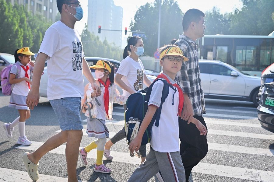 Primary school students are accompanied by their guardians as they head for classes on the the first day of the new semester in Beijing, China, on 1 September 2023. (Wang Zhao/AFP)