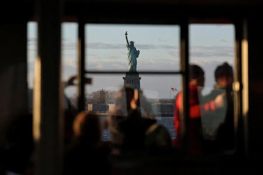 People ride on the deck of the Staten Island Ferry as it passes the Statue of Liberty in New York Harbor in New York City, US, on 28 November 2025.
