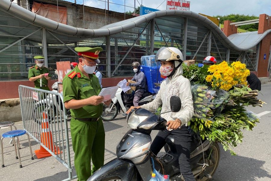 Vietnam police officers inspect authorised travel documents of commuters at a checkpoint during the first day of the extended lockdown in Hanoi, Vietnam, 6 September 2021. (Stringer/Reuters)