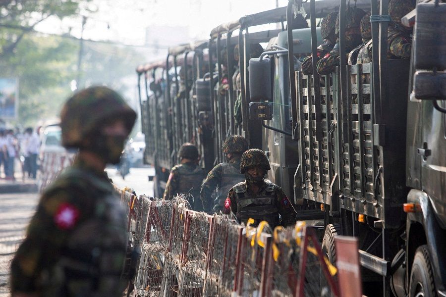 Soldiers stand next to military vehicles as people gather to protest against the military coup, in Yangon, Myanmar, 15 February 2021. (Stringer/File Photo/Reuters)