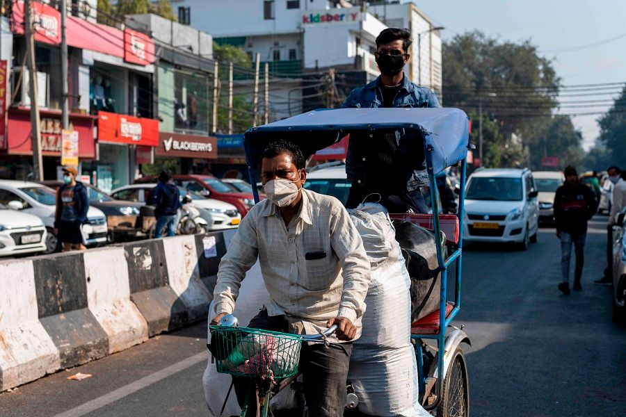 A rickshaw driver wearing a face mask transports goods along a street in a market area in New Delhi, India on 19 December 2020. (Jewel Samad/AFP)