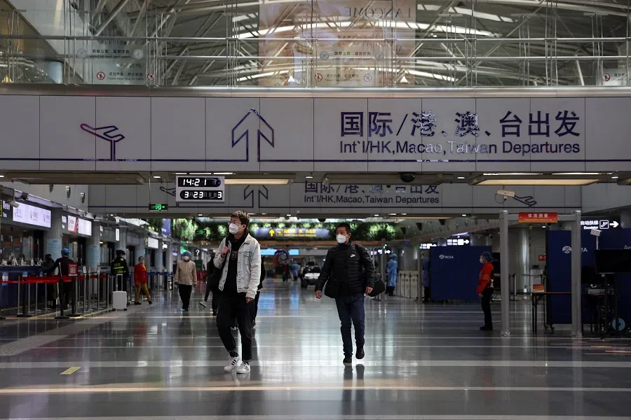 Travellers walk at a terminal hall of the Beijing Capital International Airport in Beijing, China, 23 March 2022. (Tingshu Wang/Reuters)