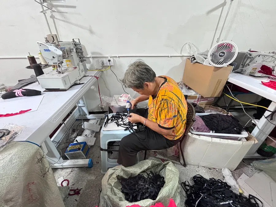 An employee of Medusa Garments factory working in front of a sewing machine.