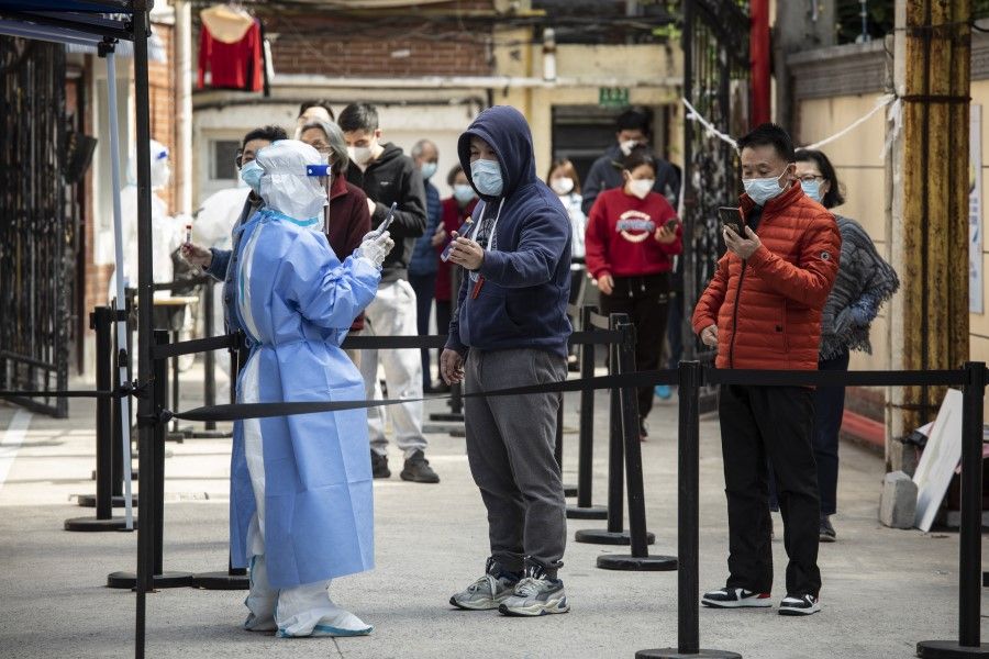 Residents show their health codes on mobile phones before taking part in a round of Covid-19 testing during a lockdown in Shanghai, China, on 18 April 2022. (Qilai Shen/Bloomberg)