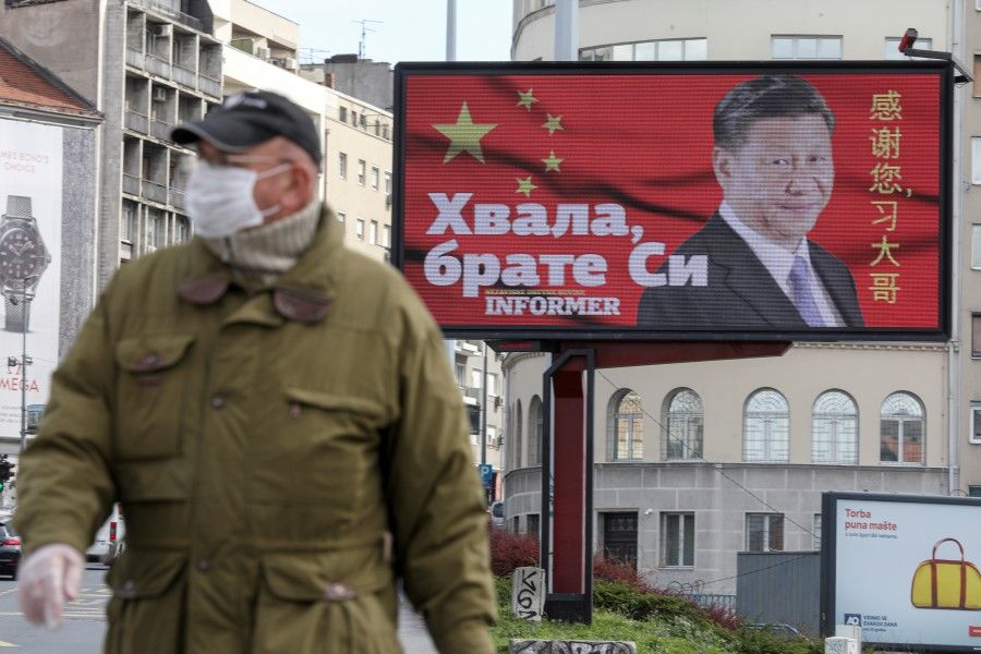 A man wearing a protective mask passes by a billboard depicting Chinese President Xi Jinping as the spread of the coronavirus disease (COVID-19) continues in Belgrade, Serbia, 1 April 2020. The text on the billboard reads "Thanks, brother Xi." (Djordje Kojadinovic/REUTERS)