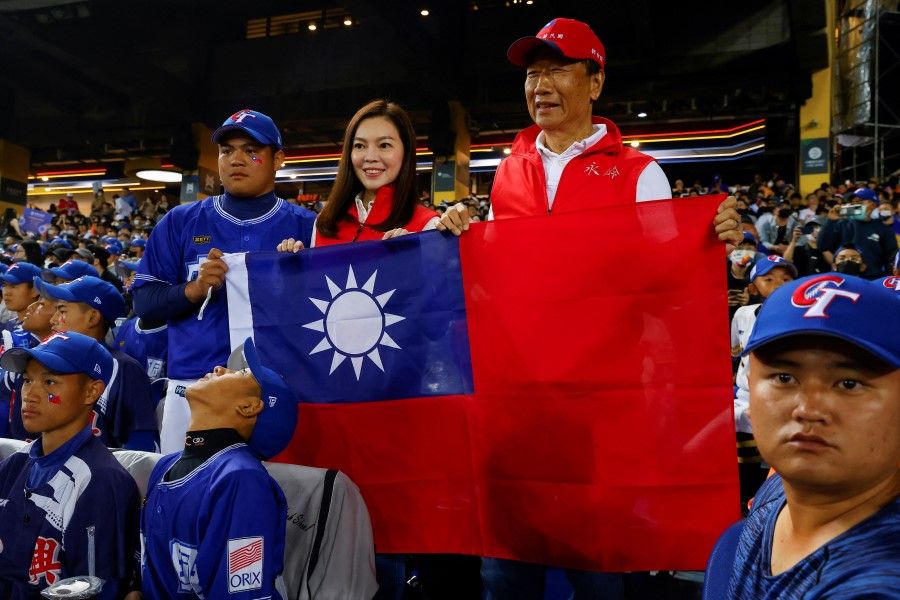 Terry Gou, founder of Taiwan's Foxconn poses for photos while holding the Taiwan flag before the match between Taiwan and Panama in the 2023 World Baseball Classic game in Taichung, Taiwan, 8 March 2023. (Ann Wang/Reuters)