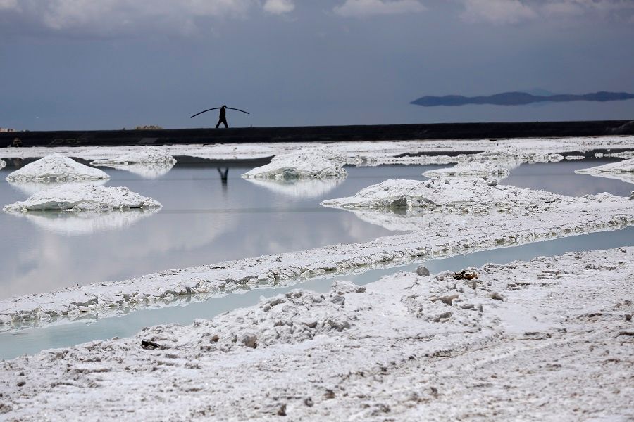 A worker walks near an evaporation pool where lithium bicarbonate is isolated from salt brine during the process of lithium production at the Uyuni Salt Flats in Uyuni, Bolivia, on 29 January 2014. (Noah Friedman-Rudovsky/Bloomberg)