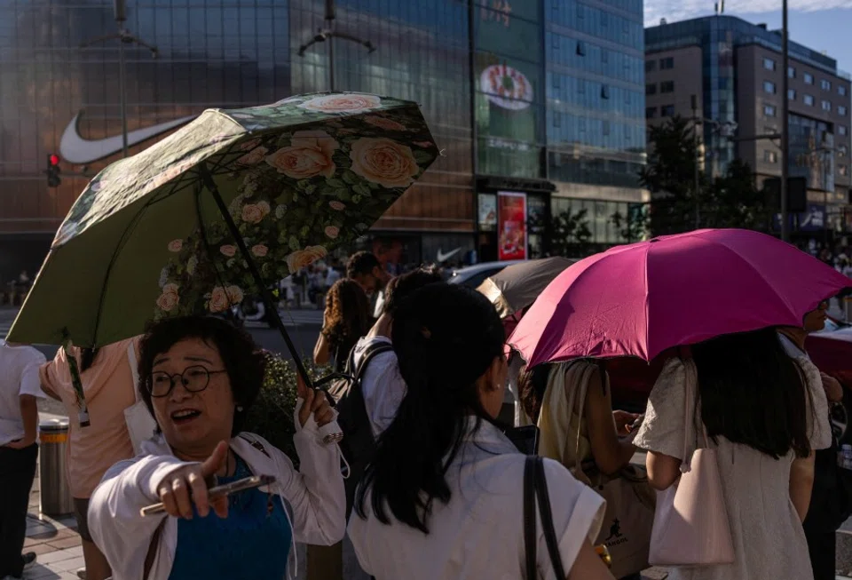 Women on the street in Beijing, China, on 7 August 2025. (Maxim Shemetov/Reuters)