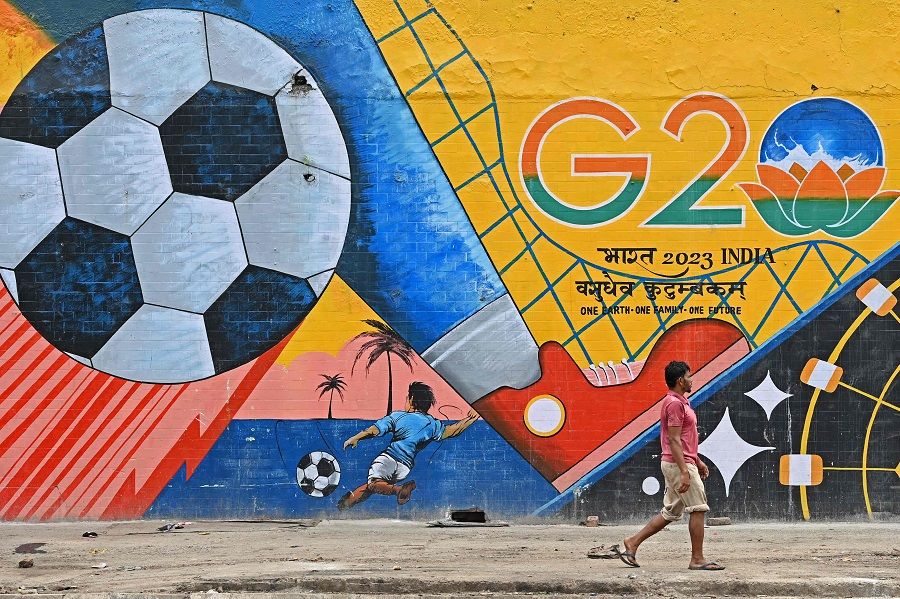 A man walks past a wall mural with India's G20 summit logo in New Delhi, India, on 22 August 2023. (Sajjad Hussain/AFP)