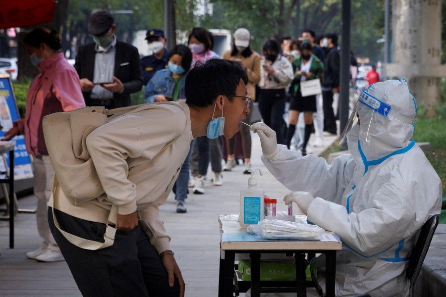 A man gets a swab at a nucleic acid testing station set up to trace possible coronavirus disease (COVID-19) outbreaks in Beijing, China, 7 October 2022. (Thomas Peter/Reuters)