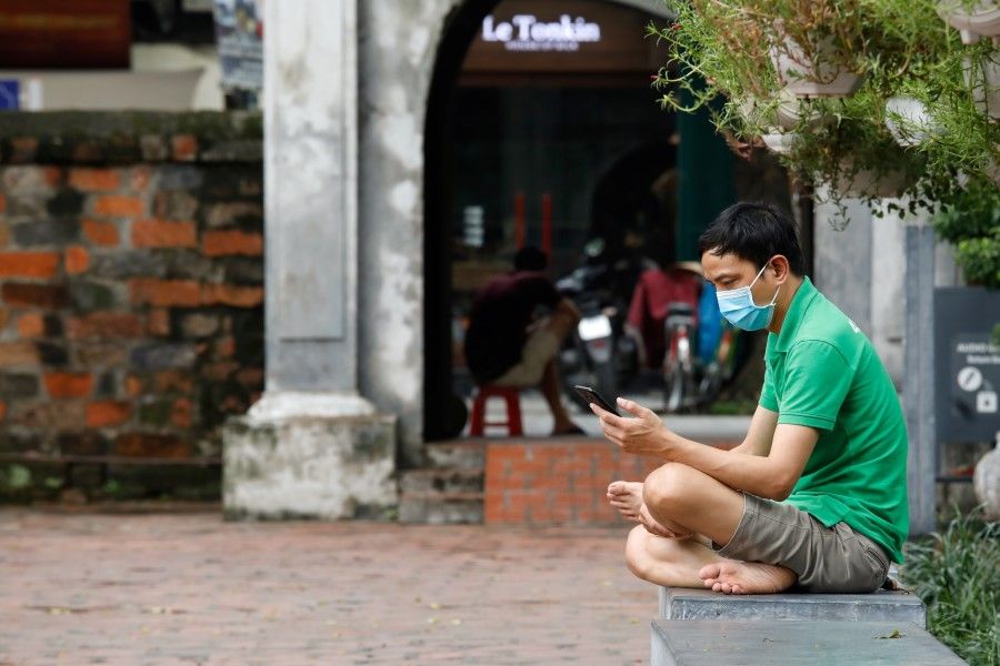 A man wearing a protective face mask looks at a smart phone amid the coronavirus disease (COVID-19) outbreak, at the temple of literature in Hanoi, Vietnam, 7 August 2020. (Kham/REUTERS)