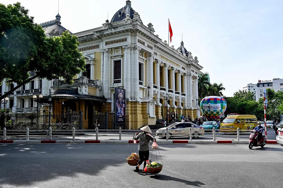 A vendor carries fruits for sale in front of the Opera House in Hanoi on 24 October 2024. (Nhac Nguyen/AFP)