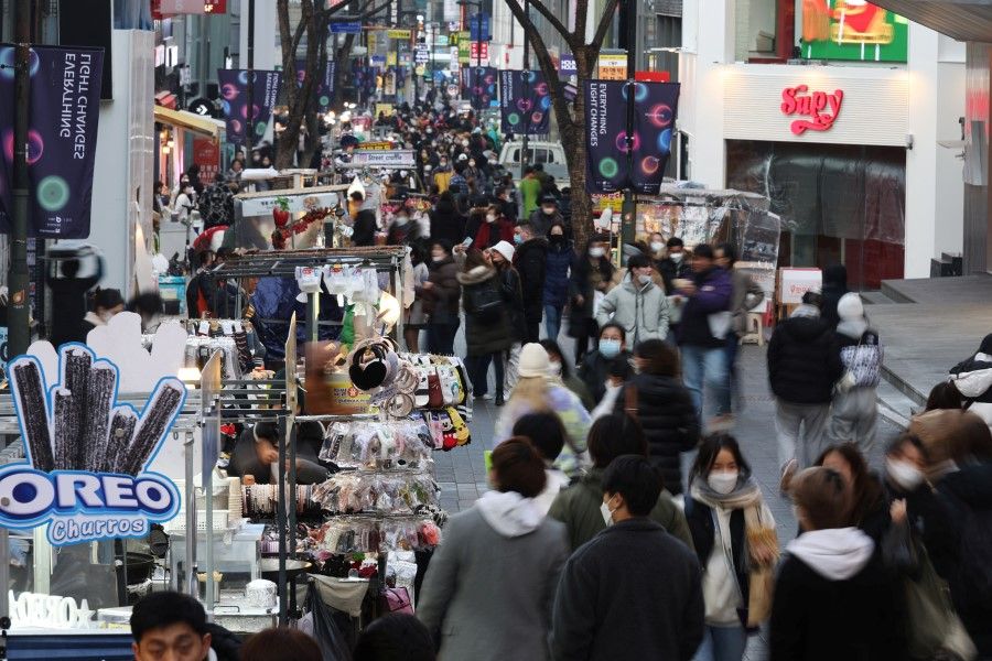 Street vendors (left) wait for customers at Myeongdong shopping district in Seoul, South Korea, 9 January 2023. (Kim Hong-Ji/Reuters)