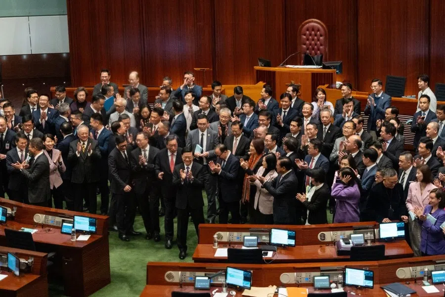 John Lee, Hong Kong's chief executive, front centre, applauses with lawmakers following the passing of Basic Law Article 23 legislation at the Legislative Council in Hong Kong, China, on 19 March 2024. Hong Kong has fast-tracked into law a domestic security legislation that critics say could muzzle open economic discussion and tighten control over foreign bodies operating in the global finance hub. (Chan Long Hei/Bloomberg)