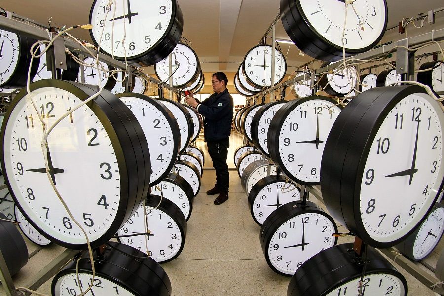 A technician checks hanging clocks at a workshop of a clock company in Yantai, Shandong province, China, on 15 December 2020. (STR/AFP)
