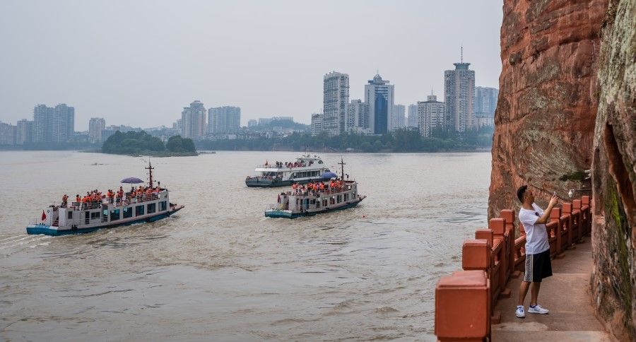 Tourist boats on the confluence of the Min River and Dadu River with Leshan town cityscape in the background, July 2019. (iStock)