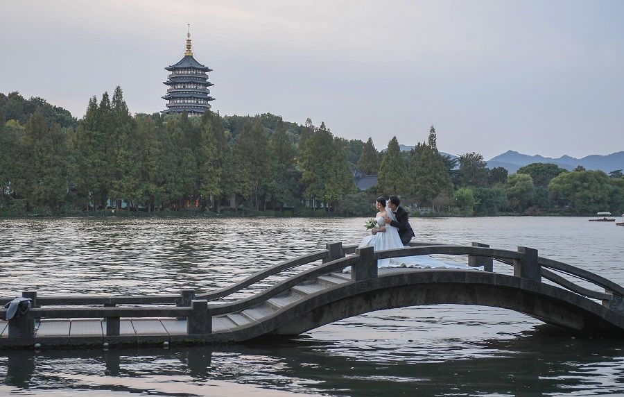 A couple takes their wedding photographs with the Leifeng Pagoda in the background, on West Lake in Hangzhou, Zhejiang province, China, 25 October 2022. (CNS)