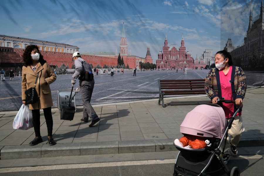 People walk past an image of Moscow's Red Square, outside a supermarket featuring Russian goods in Beijing, China, 1 April 2022. (Tingshu Wang/Reuters)