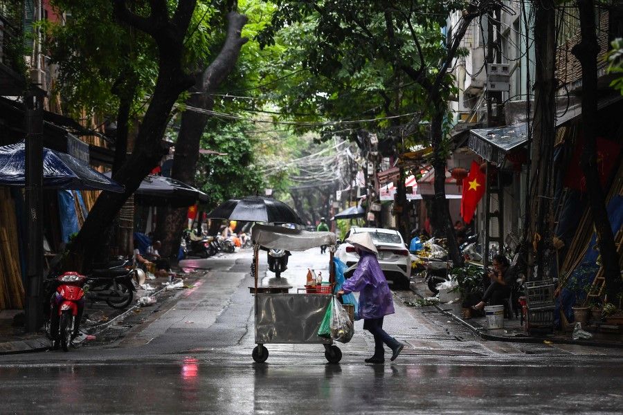 A street vendor pushes her cart in the rain in Hanoi, 15 October 2020. (Nhac Nguyen/AFP)