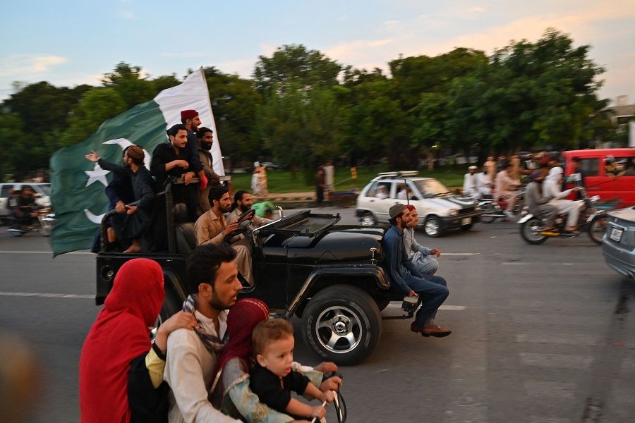 Men wave Pakistan's national flag while riding a car to celebrate the country's Independence Day in Islamabad, Pakistan, on 14 August 2023. (Farooq Naeem/AFP)