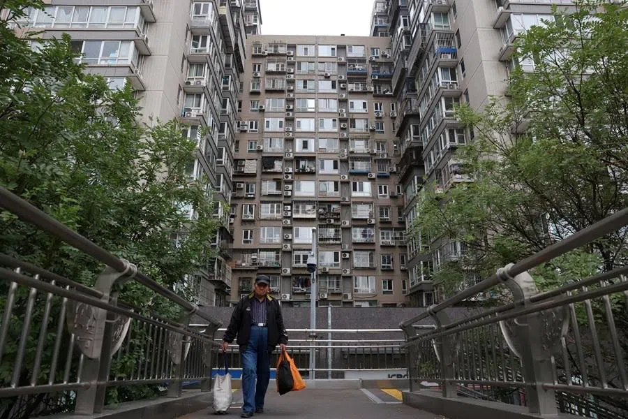 A man walks on a pedestrian bridge near residential buildings in Beijing, China, on 17 October 2024.
