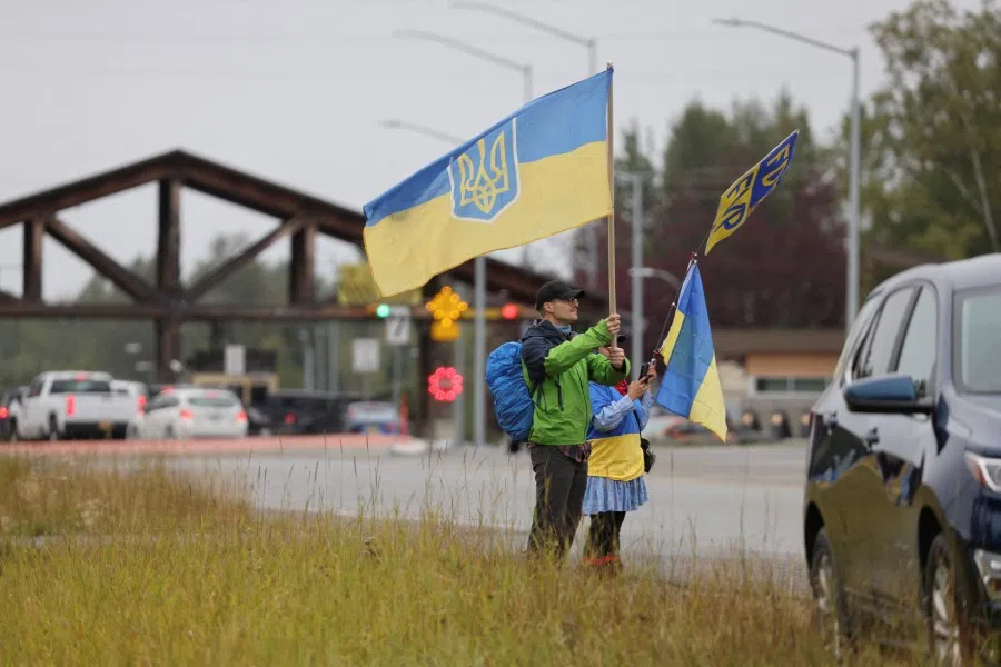 People hold flags as they take part in a demonstration in support of Ukraine, on the day Russia’s President Vladimir Putin meets with US President Donald Trump to negotiate an end to the war in Ukraine, outside Joint Base Elmendorf-Richardson in Anchorage, Alaska, US, on 15 August 2025. (Nathaniel Wilder/Reuters)