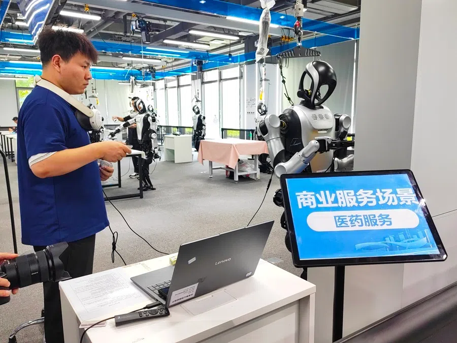 Data trainers at the Beijing Shijingshan Humanoid Robot Data Training Center teach robots how to pick up medicine at a pharmacy on 13 August 2026.