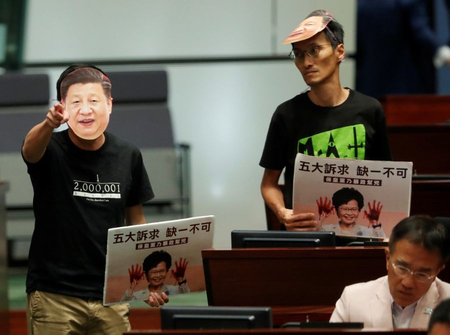 The impression that the Hong Kongers have of the central government and the mainland is directly related to the LOCPG's work. In the photo, a lawmaker in a mask depicting Chinese President Xi Jinping protests as Hong Kong Chief Executive Carrie Lam attempts to deliver her annual policy address at the Legislative Council in Hong Kong on 16 October 2019. (Kim Kyung-Hoon/Reuters)