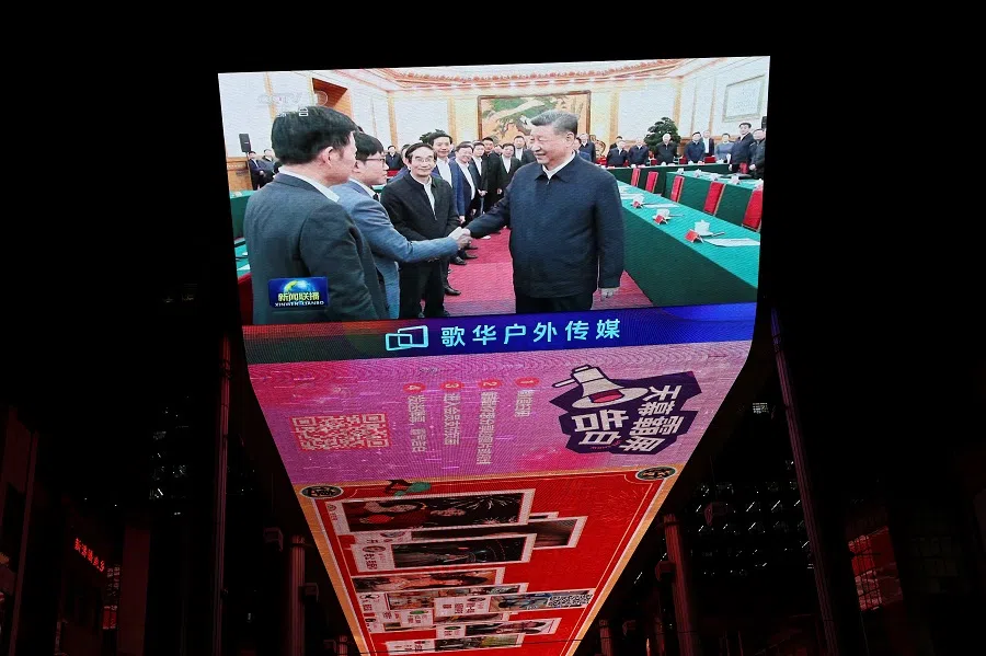 A giant screen shows news footage of Chinese President Xi Jinping shaking hands with DeepSeek founder Liang Wenfeng during a symposium on private enterprises, at a shopping complex in Beijing, China, 17 February 2025. (Florence Lo/Reuters)