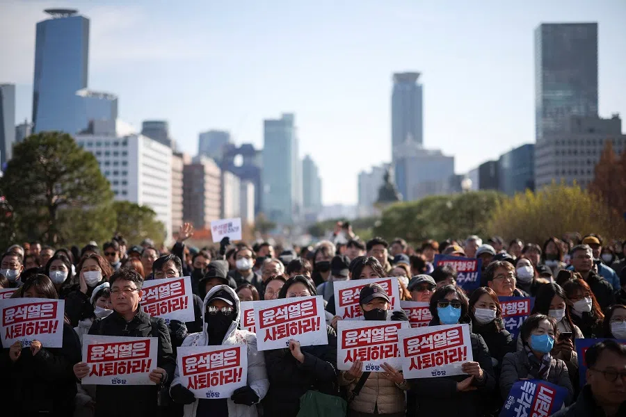 Protesters hold up signs that read “Step down President Yoon Suk-yeol” as people and lawmakers attend a rally condemning the South Korean president’s failed surprise declaration of martial law, and to call for his resignation, at the national assembly in Seoul, South Korea, on 4 December 2024. (Kim Hong-Ji/Reuters)