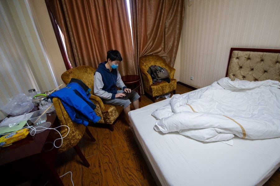 A Chinese student wearing a face mask uses a laptop in a room at a hotel being used for centralised quarantine in Taiyuan, Shanxi province, 17 March, 2020. (CNS via REUTERS)