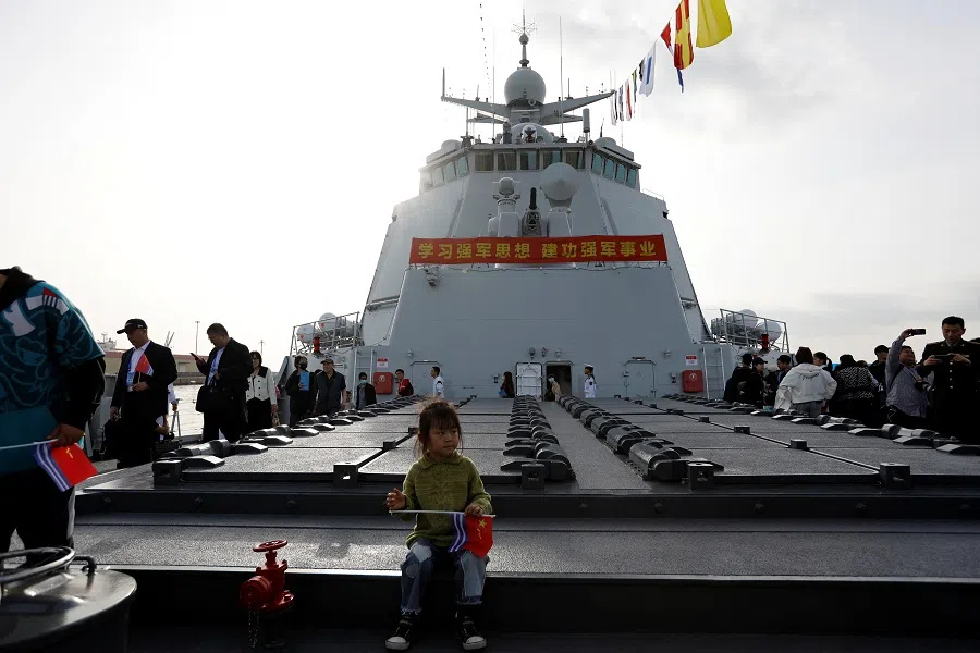 A child sits on Guiyang (119), a Type 052D guided missile destroyer, as the PLAN opens warships for public viewing to mark its upcoming 75th founding anniversary, at the port in Qingdao, Shandong province, China, on 20 April 2024. (Florence Lo/Reuters)