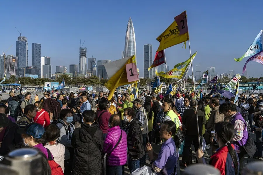 Tour guides wait to collect tour groups from Hong Kong outside the Shenzhen Bay border crossing in Shenzhen, China, on 20 January 2024. (Qilai Shen/Bloomberg)