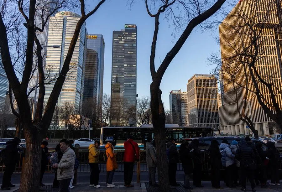 People queue as they wait for a bus, with skyscrapers of the central business district in the background in Beijing, China, on 5 January 2026. (Maxim Shemetov/Reuters)