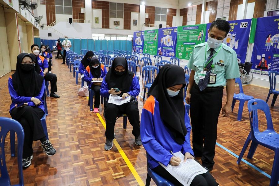 A medical worker observes secondary school students after they receive a dose of the Covid-19 vaccine at a school, in Putrajaya, Malaysia, 20 September 2021. (Lim Huey Teng/Reuters)